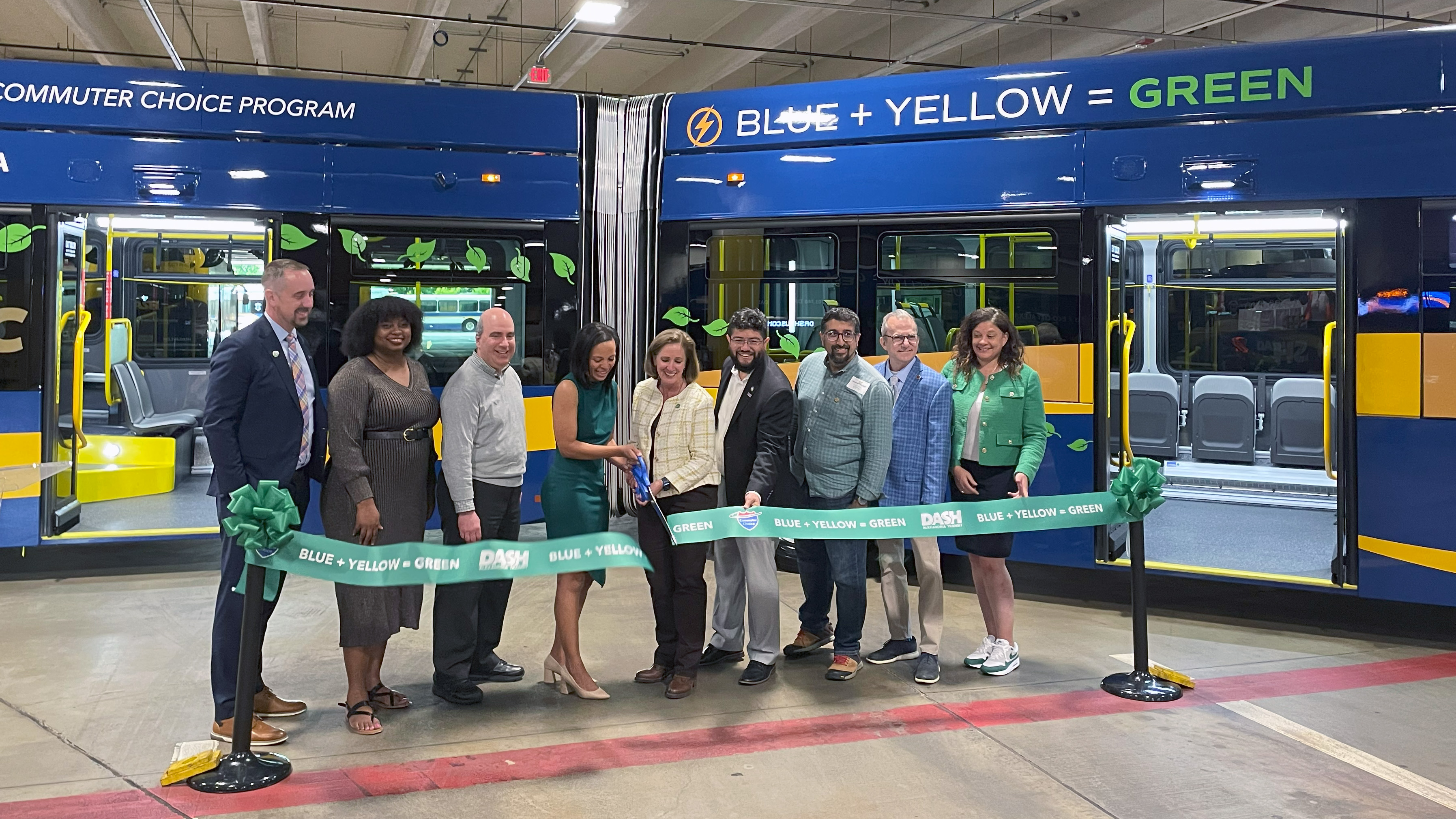 A group of people cutting a green ribbon in front of an articulated bus